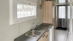 A modern kitchen with a large window, a sink, and wooden cabinets.
