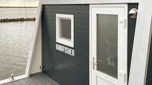 A boat with a dark gray exterior, a white door, and a window. The name "KINGFISHER" is visible on the side.
