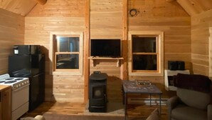 Interior acogedor de una cabaña de troncos con cocina, chimenea, sofá y mesa de comedor.
