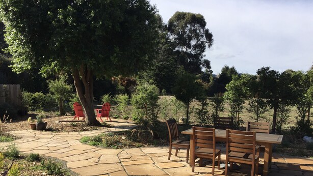 A patio area with stone flooring, wooden furniture, and red chairs. - Beautiful, private, sunny, ideal location, 31 night minimum (Carmel Valley)