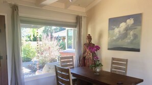A dining area with a wooden table, chairs, a Buddha statue, and a painting of clouds. - Beautiful, private, sunny, ideal location, 31 night minimum (Carmel Valley)
