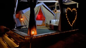 Un hébergement sous tente comprenant un lit, un coin salon et une décoration lumineuse en forme de cœur.