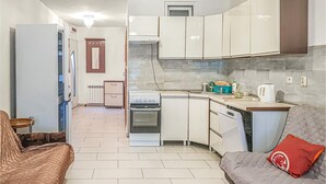 A compact kitchen with white cabinets, a stove, and a dishwasher. There is a small dining area with a table and chairs.