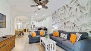 Una sala de estar moderna con un sofá gris, una mesa de centro de madera y un panel decorativo en la pared.