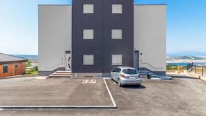 Un bâtiment moderne doté d’un espace de stationnement, d’une voiture et d’un scooter.