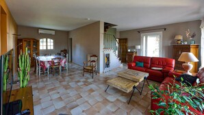 A spacious living room with a red sofa, a wooden coffee table, and a dining area with a table and chairs. - Cozy home in Lançon-Provence (Lançon-Provence)