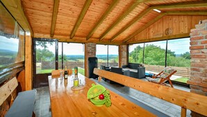 Un intérieur en bois comprenant un coin repas, de grandes fenêtres et une vue sur la campagne.