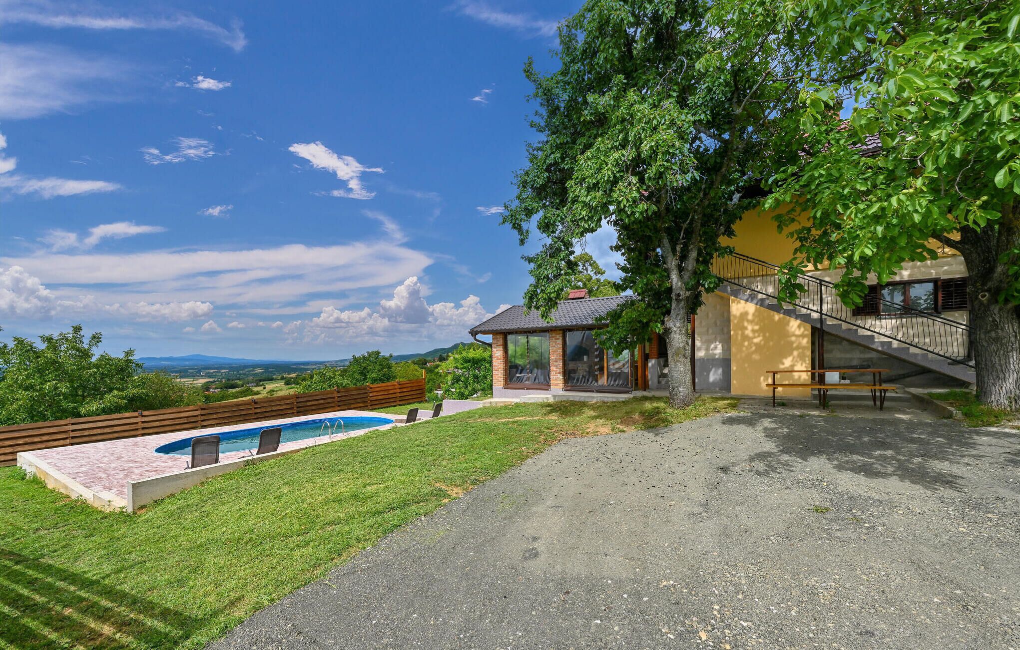 A house with a swimming pool, a bench, and a staircase leading to a balcony.