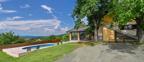 A house with a swimming pool, a bench, and a staircase leading to a balcony.