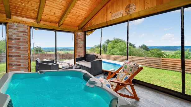 Un espace extérieur abrité comprenant un jacuzzi, des sièges et une vue sur le paysage.