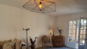 Una sala de estar con un sofá, una silla, un mueble, una lámpara y un aplique de techo con diseño geométrico.