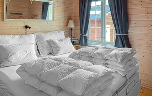 A wooden-paneled room with a bed, a mirror, a lamp, and a window with curtains. - Amazing home in Tisleidalen with sauna (Tisleidalen)