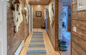 A wooden hallway with fur wall hangings, a patterned rug, and a lantern. - Amazing home in Tisleidalen with sauna (Tisleidalen)
