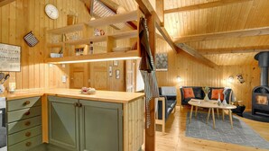 Ein Holzinnenraum mit Küche, Essbereich und Kamin.