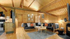 Ein gemütliches Blockhaus-Interieur mit Holzausstattung, einer Couch, einem Couchtisch und einem Kamin.