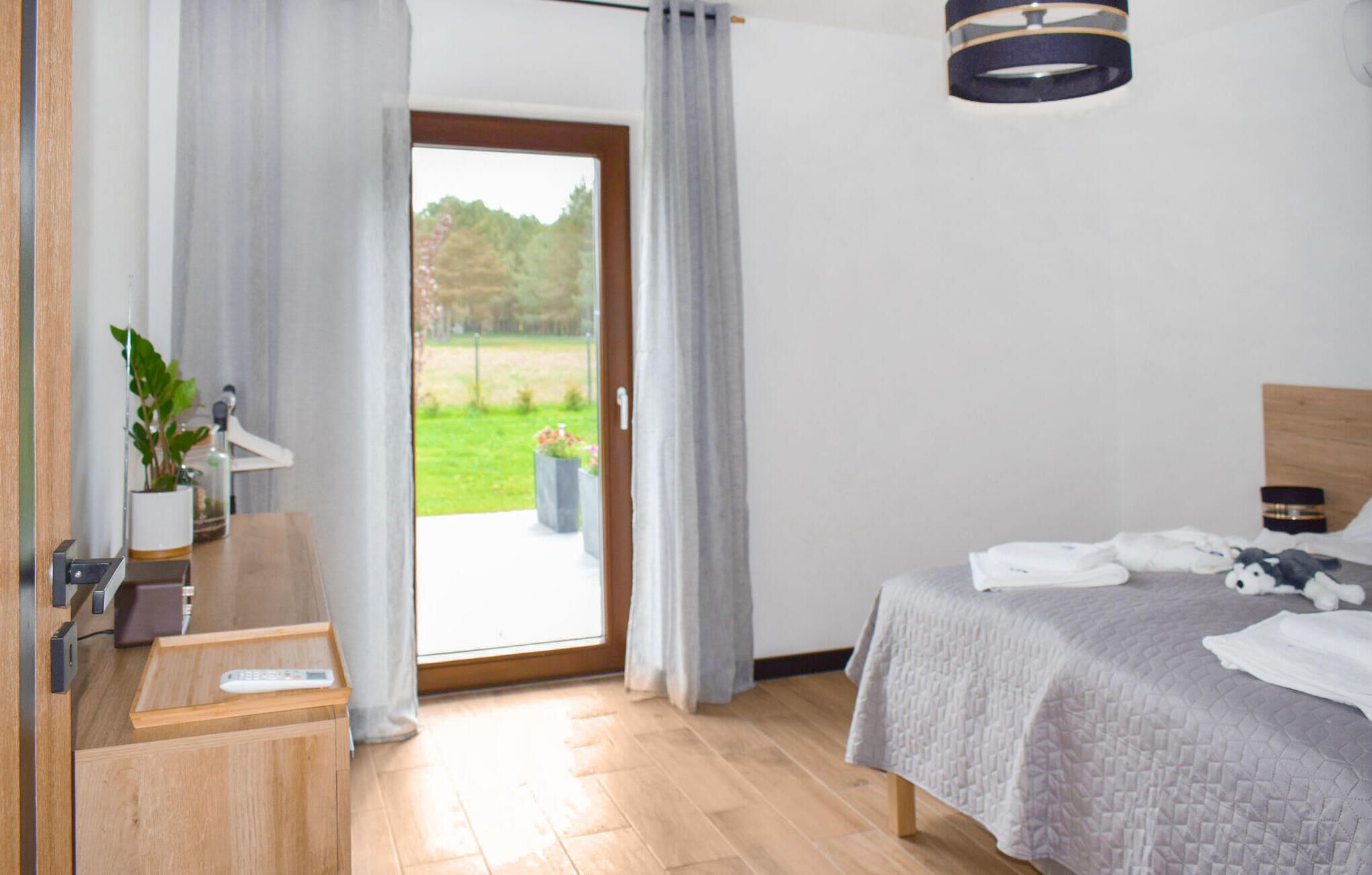 A bedroom with a bed, a bedside table, a lamp, and a view of a garden through a sliding door.