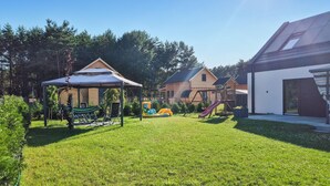 A well-maintained backyard with a hammock, play equipment, and a covered seating area. - Amazing home in Nowe Warpno with sauna (Nowe Warpno)