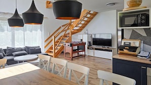 A modern living space with a loft bedroom, a dining area, and a kitchen. - Amazing home in Nowe Warpno with sauna (Nowe Warpno)