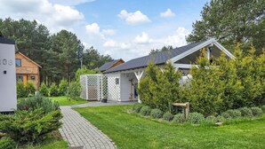A residential property with a paved pathway, a wooden house, and a fenced garden area. - Amazing home in Nowe Warpno with sauna (Nowe Warpno)
