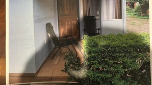 Ett rum med en dörr av trä, en stol och ett fönster med gardiner.