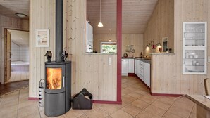 A cozy cabin interior with a wood-burning stove, a visible bathroom, and a kitchen area.