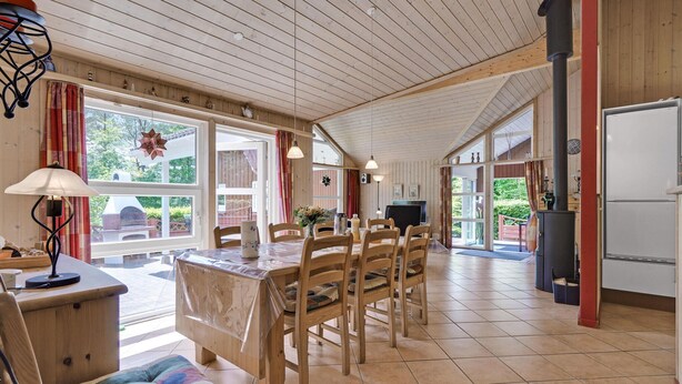 A spacious dining area with wooden furniture, large windows, and a fireplace.