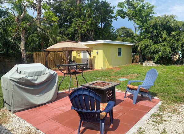 Enjoy al fresco dining and relaxation in this outdoor space, featuring a barbecue grill, table, and fire pit.