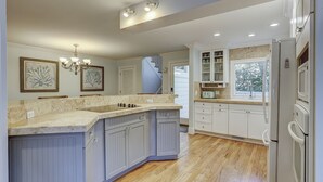 A kitchen with a central island, white cabinets, a refrigerator, and a window with a view.