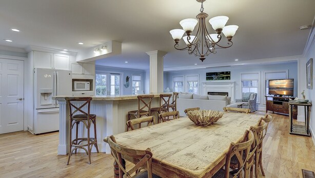 A spacious kitchen with white cabinetry, a wooden dining table, and a chandelier.