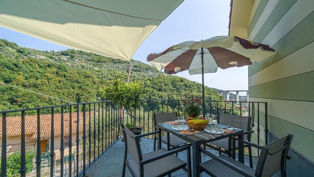 A balcony with a table set for two, a chair, and a potted plant. - Nice home in Avegno with house sea view (Avegno)