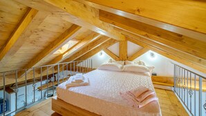 A high-ceilinged room with a wooden ceiling and a bed with pillows and folded towels. - Nice home in Avegno with house sea view (Avegno)