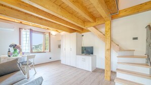 A spacious living area with a wooden ceiling, a staircase, and a TV on a cabinet. - Nice home in Avegno with house sea view (Avegno)