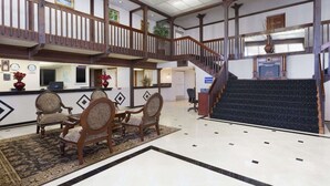 A hotel lobby with a reception desk, seating area, staircase, and a view of the city. - Travelodge by Wyndham Orange County Airport/ Costa Mesa (Costa Mesa)