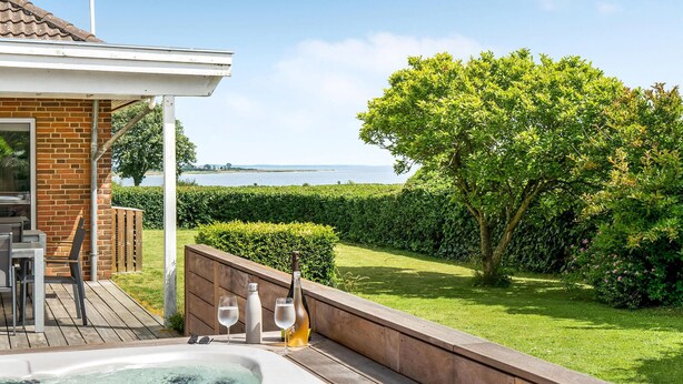 Un patio con un jacuzzi, una terraza de madera y vista al mar.