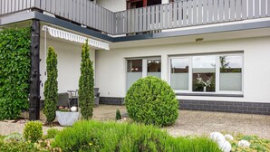 Een huis met twee verdiepingen, een balkon en een tuin met verschillende planten, plus een raam met uitzicht.