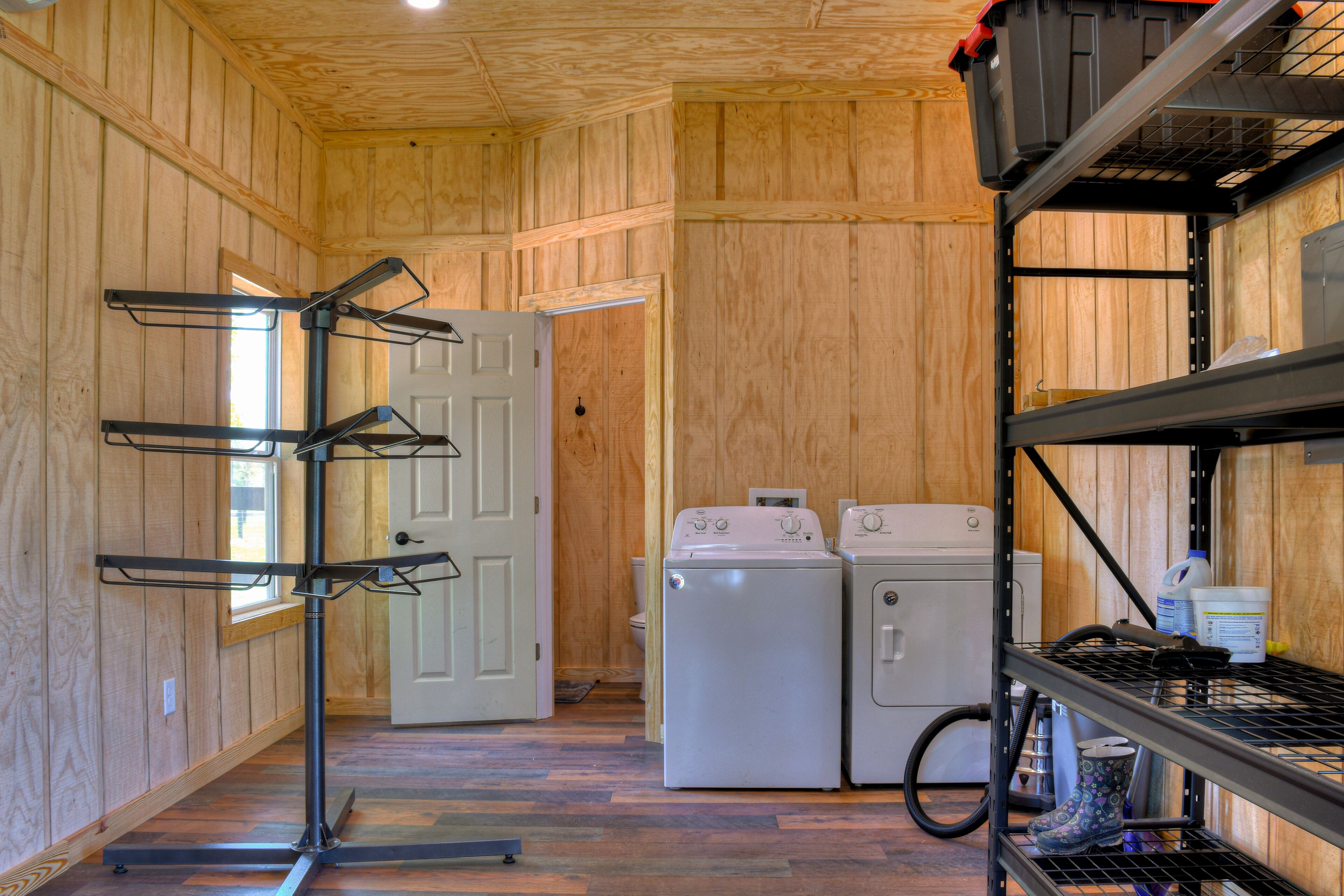 A laundry area with a washer and dryer, metal shelves, and a door leading to another room.