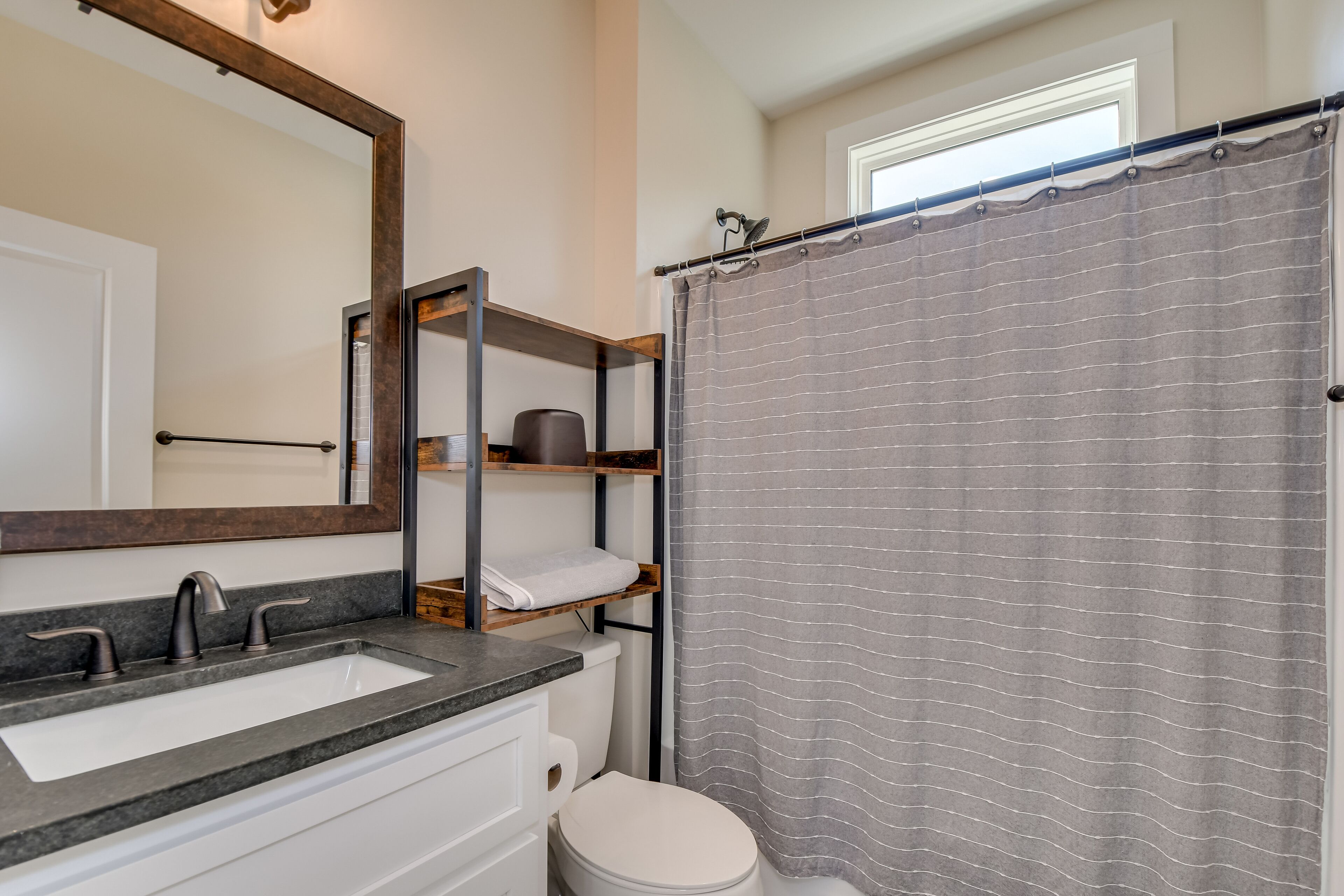 A bathroom with a white sink, a mirror, a toilet, and a shower curtain.