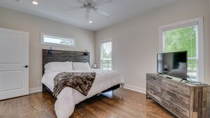 Ein Schlafzimmer mit einem Bett, einem Fernseher auf einer Holzkommode und einem Deckenventilator.