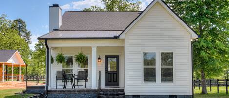 A white single-story house with a front porch, a chimney, and a small garden area.