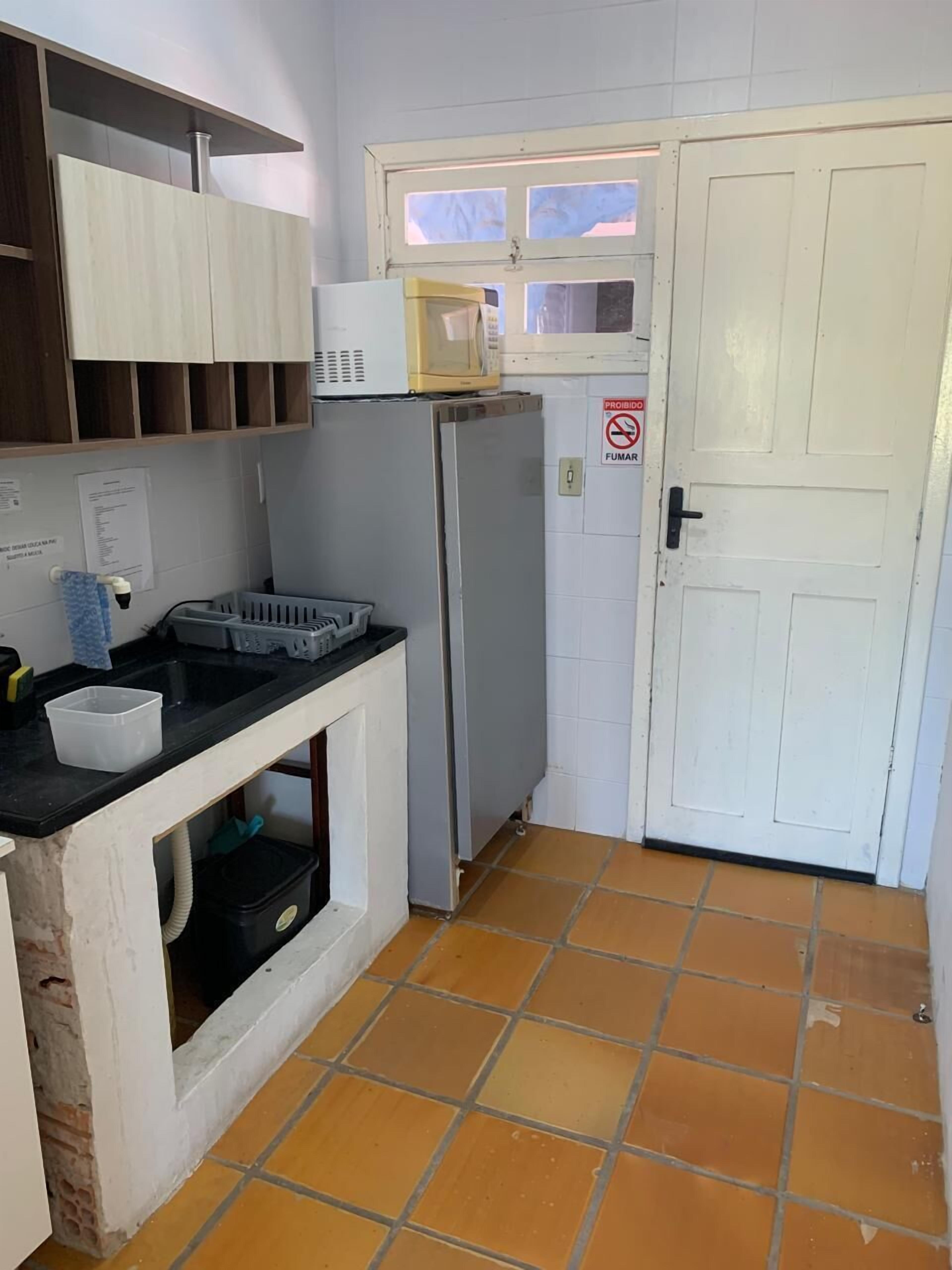 A compact kitchen with a refrigerator, a microwave, and a sink.