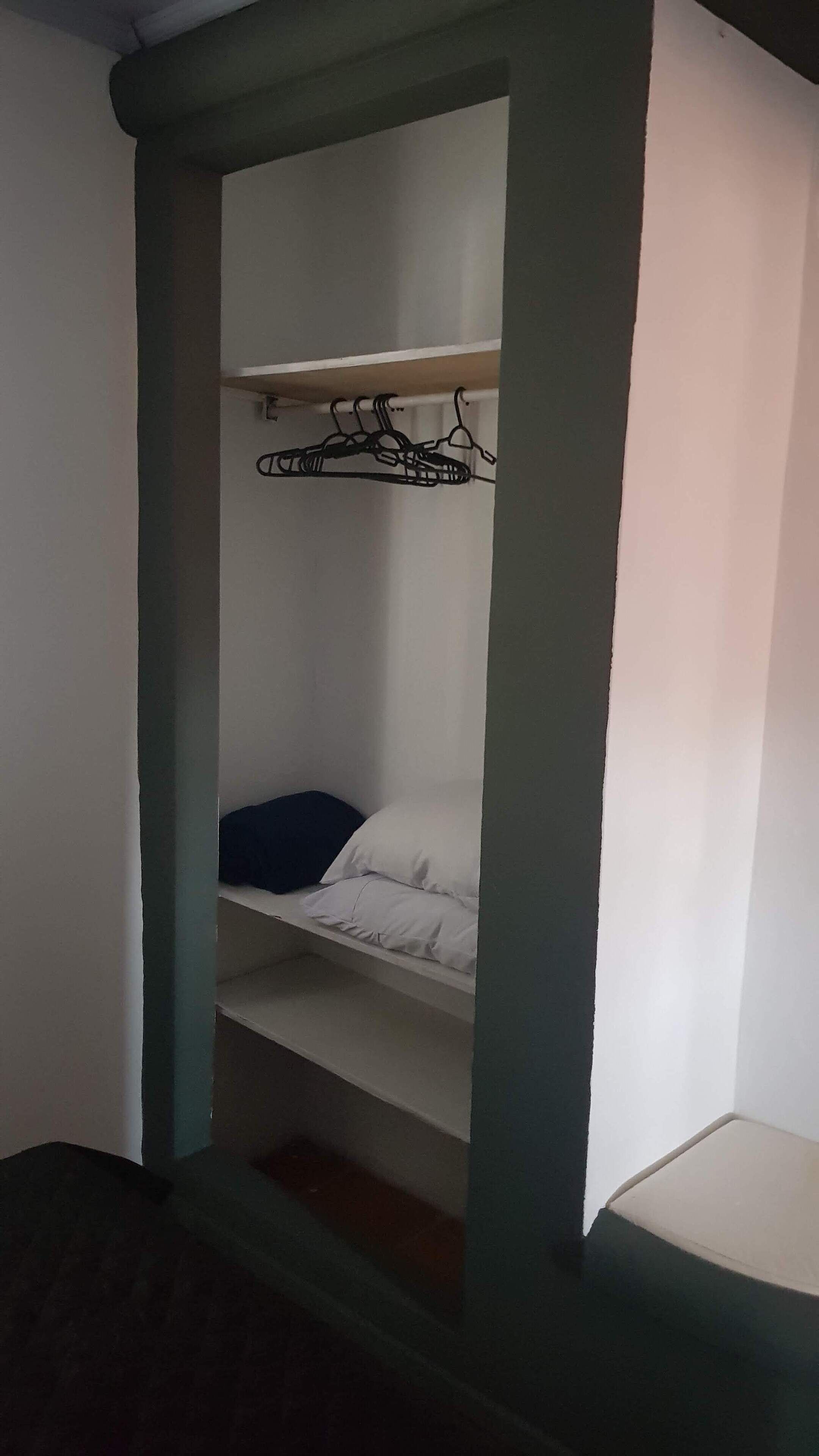 A bunk bed with a hanging clothes rack above it.