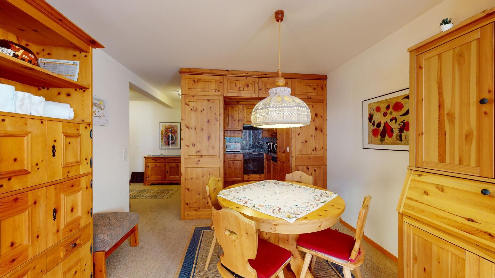 A wooden interior with a dining table, chairs, and a kitchen area with wooden cabinets and appliances.