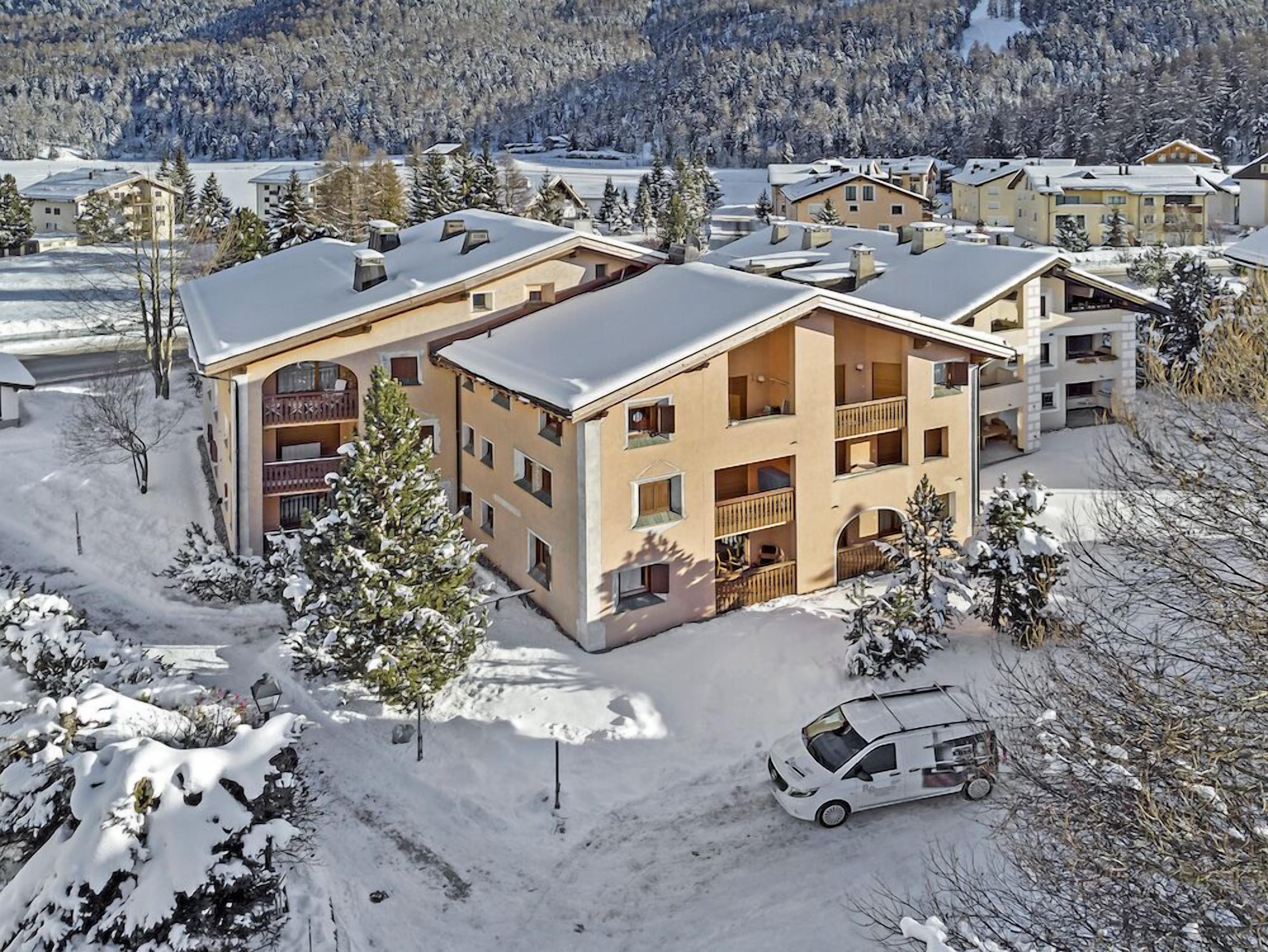 Un hôtel à plusieurs étages, entouré d’un paysage enneigé, doté de balcons et d’un espace de stationnement.