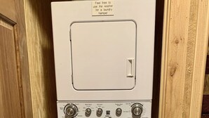 Un appareil compact combinant lave-linge et sèche-linge, doté d’un lave-linge à chargement frontal, d’un sèche-linge à chargement par le haut et d’un panneau de commande avec divers réglages.