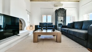 A modern living room with a large flat-screen TV, a wooden coffee table, and two dark sofas. - Amazing villa (Άγιος Ιωάννης Διακοφτης)