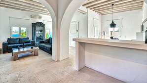 A spacious living area with a sofa set, a coffee table, and a kitchen counter with a hanging light fixture. - Amazing villa (Άγιος Ιωάννης Διακοφτης)