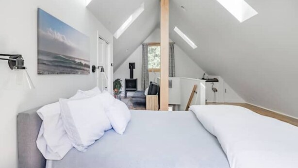 Una camera da letto con un letto grande, un quadro e una finestra sul tetto.