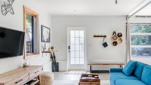 Un soggiorno moderno con TV, mobili in legno, un divano blu e una grande finestra.