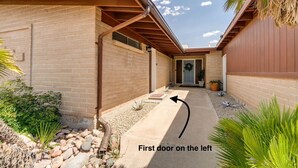 A house with a brick exterior, a covered patio, and a front door on the left.