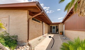 A house with a brick exterior, a covered patio, and a front door on the left.